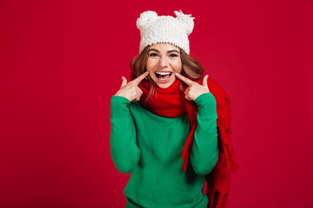 Sonriente mujer morena en suéter, sombrero gracioso y bufanda