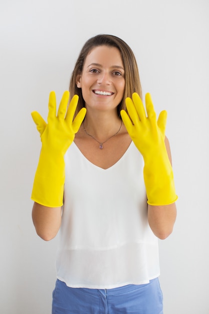 Sonriente mujer mostrando las manos en guantes de goma