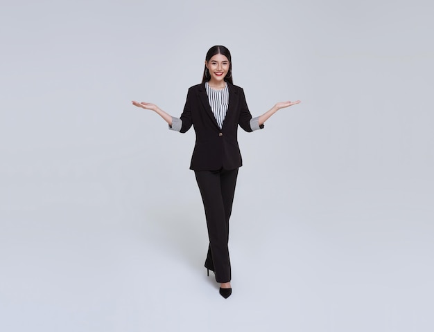Sonriente mujer de negocios asiática confiada con gesto de introducir aislado sobre fondo gris