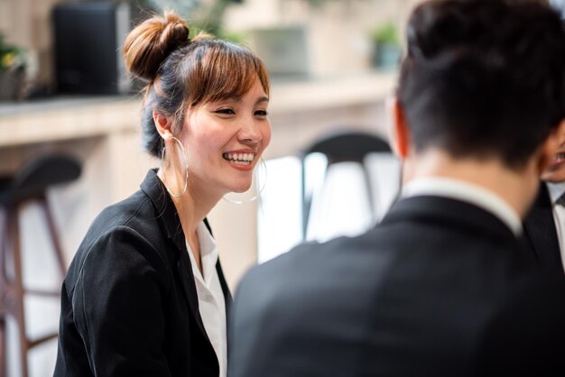 Sonriente mujer de negocios asiática mientras trabaja con un colega en la oficina