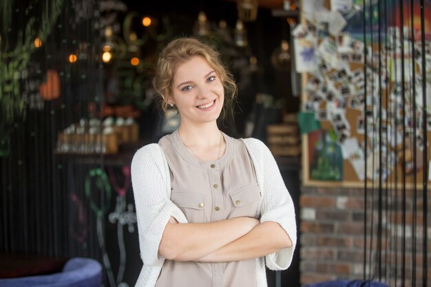 Sonriente mujer de negocios feliz posando en su propia cafetería