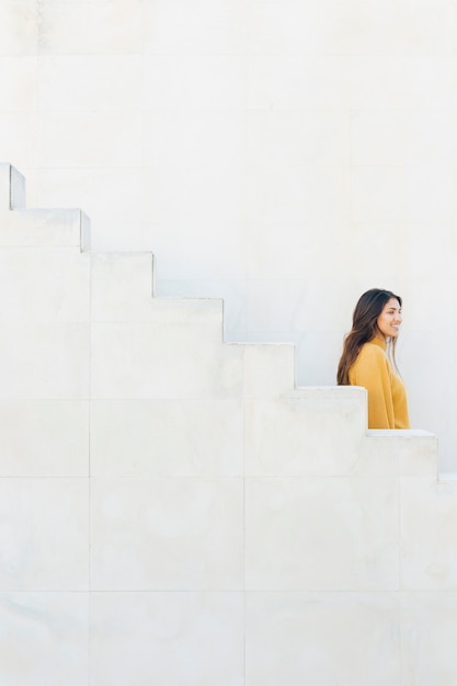 Foto gratuita sonriente mujer de pie cerca de pasos blancos