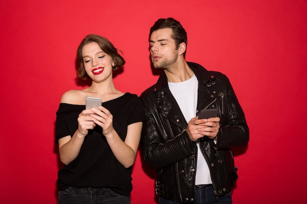 Sonriente mujer punk usando teléfono inteligente mientras el hombre lo mira