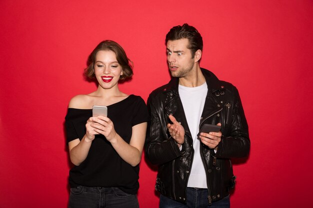 Sonriente mujer punk usando teléfono inteligente mientras el hombre lo mira