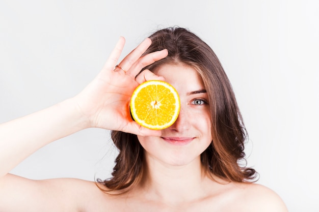 Sonriente mujer con rodaja de naranja en la cara