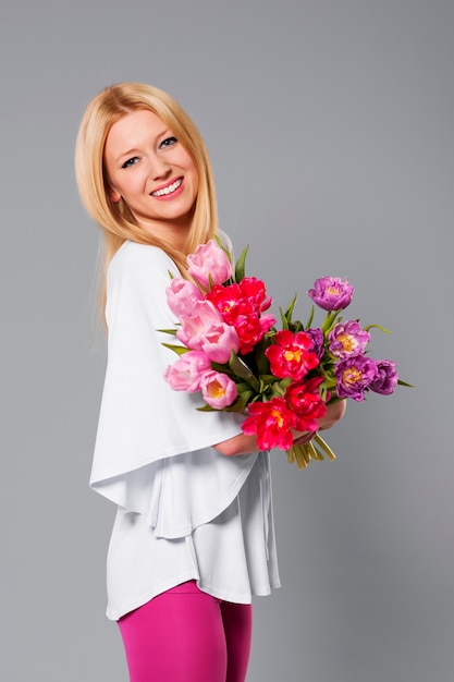 Sonriente mujer rubia con flor de primavera