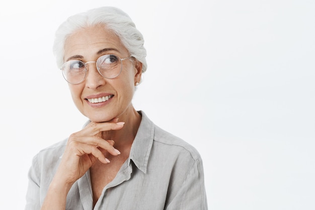 Foto gratuita sonriente mujer senior hermosa en gafas mirando en la esquina superior derecha de ensueño