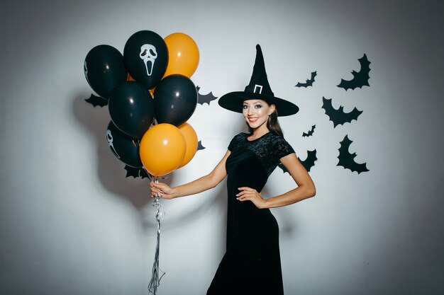 Sonriente mujer en sombrero con globos