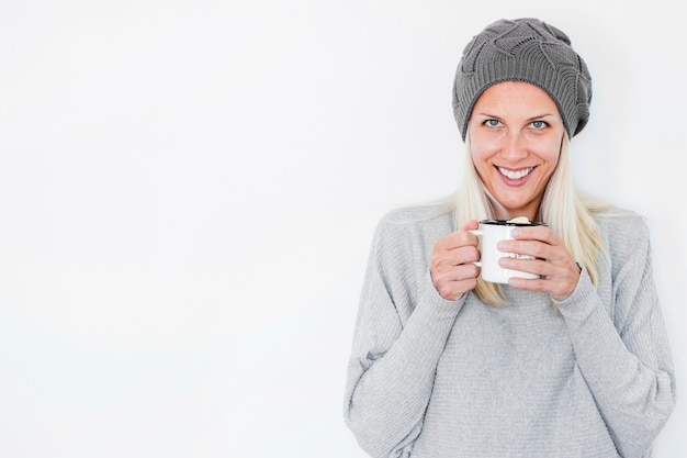 Foto gratuita sonriente mujer con sombrero sosteniendo bebida caliente