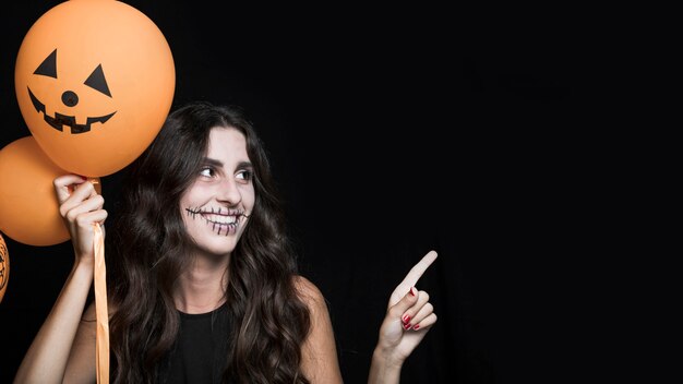 Sonriente mujer sosteniendo globos de Halloween