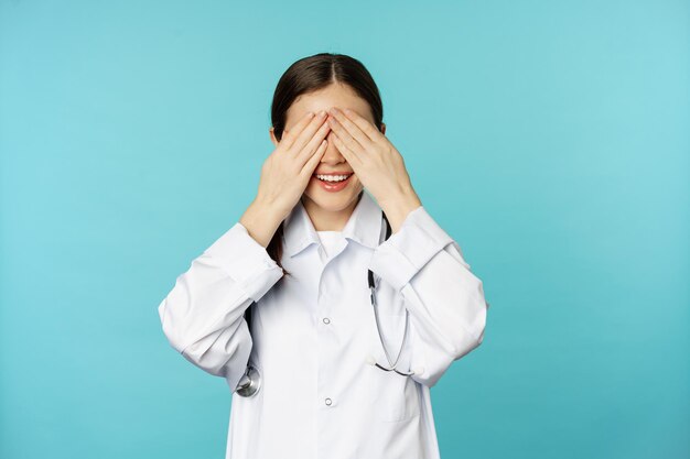 Sonriente mujer terapeuta feliz médico cubrir los ojos cerrados con las manos y esperando sorpresa anticipada...