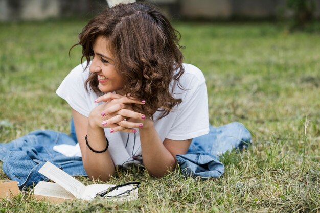 Sonriente mujer tumbada en la hierba de verano