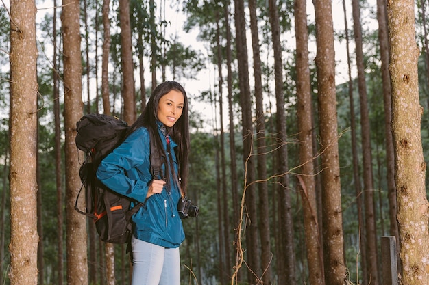 Sonriente mujer viajero con mochila y cámara