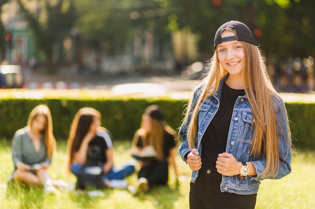 Sonriente niña adolescente cerca de amigos en el parque