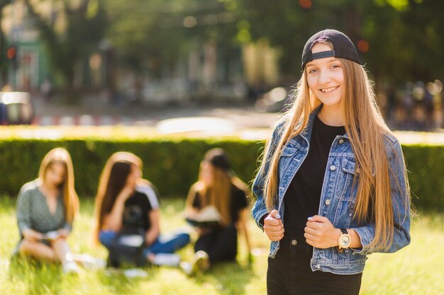 Sonriente niña adolescente cerca de amigos en el parque