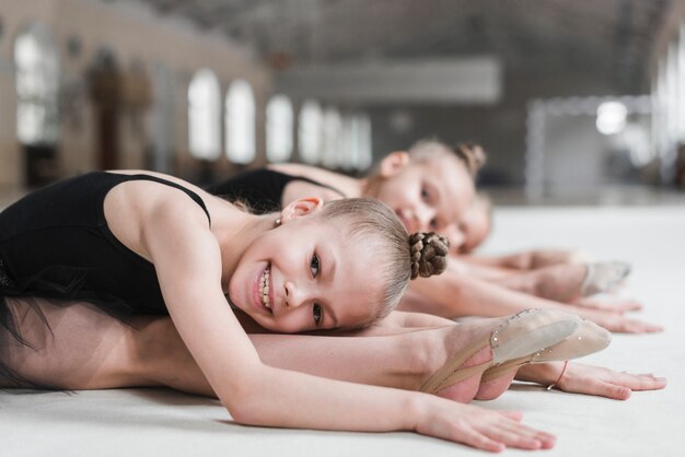 Sonriente niña bailarina posando en la pista de baile con su amiga