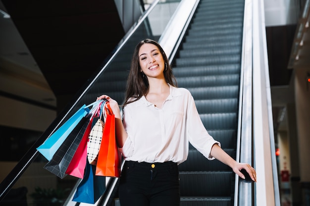 Sonriente niña con bolsas en el centro comercial