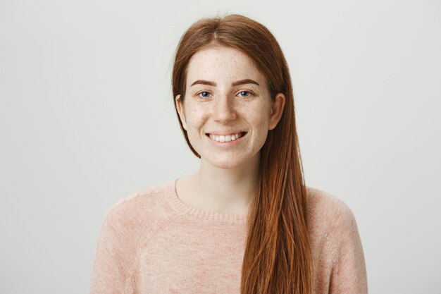 Sonriente niña bonita pelirroja con pecas sonriendo cámara