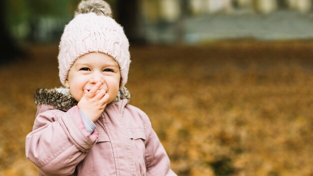 Sonriente niña comiendo bocadillo en el bosque de otoño