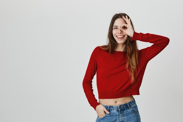 Sonriente niña despreocupada en top corto, muestra signo bien, no hay problema, todo bien