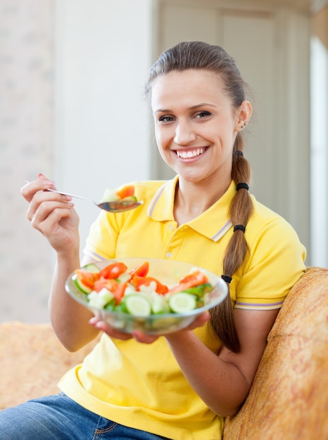 Sonriente niña saludable comer verduras ensalada