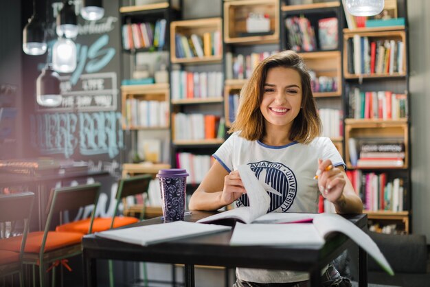 Sonriente niña sentada en la mesa con los cuadernos