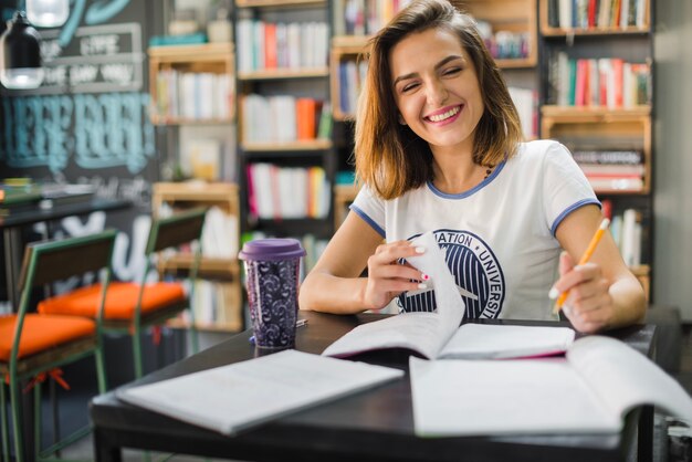 Sonriente niña sentada en la mesa con los cuadernos