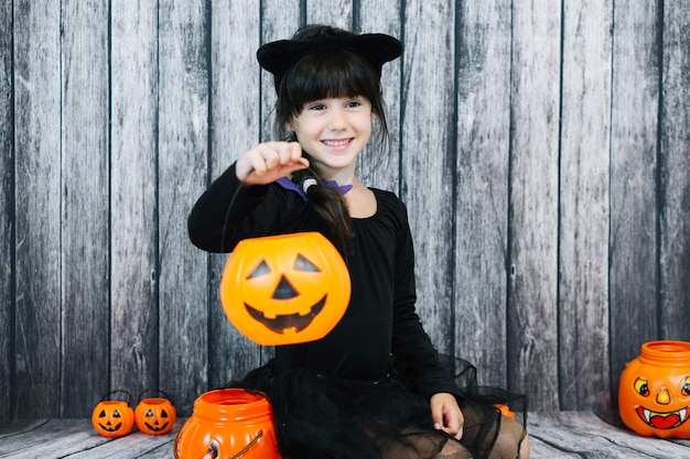 Sonriente niña sosteniendo la cesta de truco o el convite