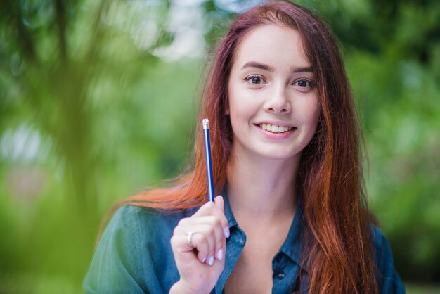 Sonriente niña sosteniendo lápiz