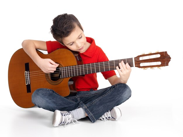 Sonriente niño caucásico está tocando la guitarra acústica - aislada sobre fondo blanco