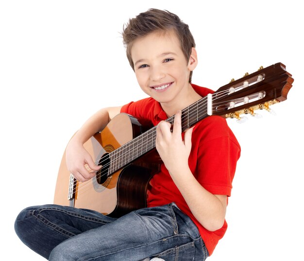 Sonriente niño caucásico está tocando la guitarra acústica -