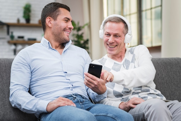 Sonriente padre e hijo sentados en el sofá