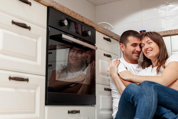 Sonriente pareja abrazándose en la cocina