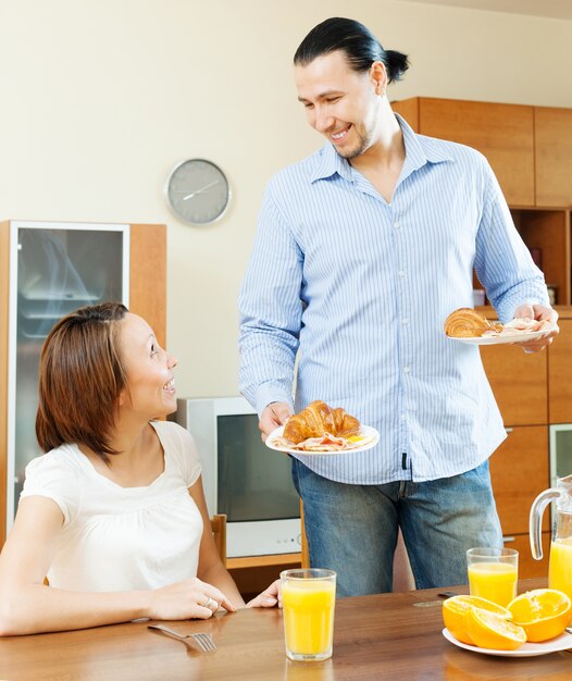 Sonriente pareja de adultos que desayunan