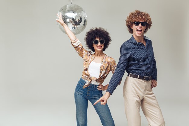 Sonriente pareja amorosa retro cerca de la bola de discoteca.