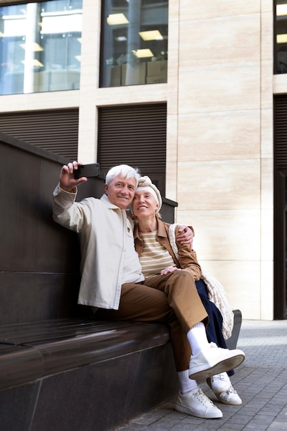 Sonriente pareja de ancianos al aire libre tomando un selfie junto con el teléfono inteligente