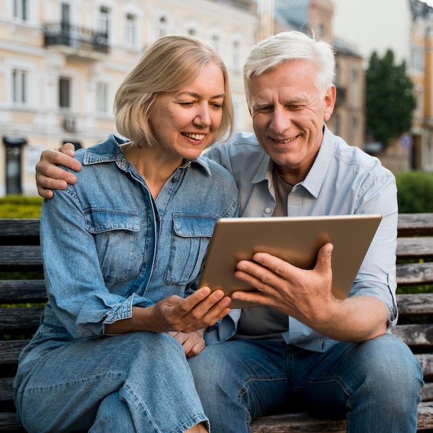 Sonriente pareja de ancianos mirando algo en tableta