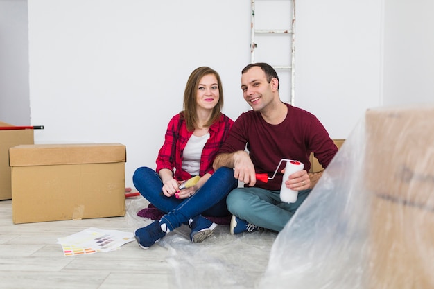 Foto gratuita sonriente pareja descansando en el piso durante la renovación