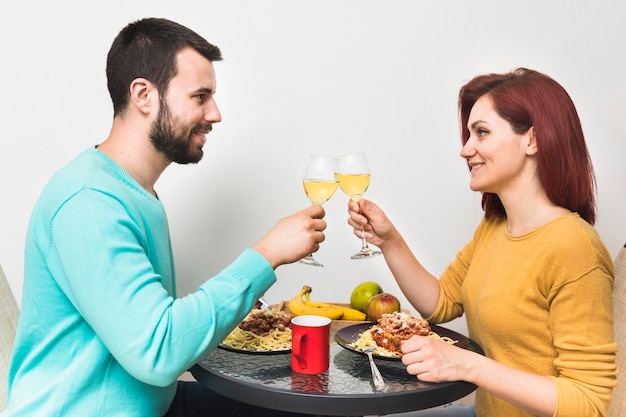 Sonriente pareja disfrutando de una bebida con comida en casa