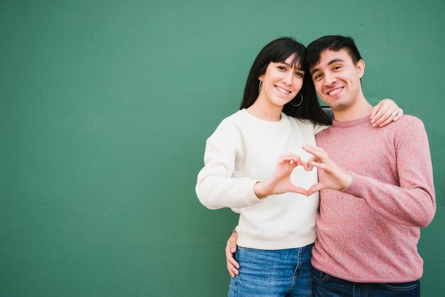 Sonriente pareja doblando las manos en forma de corazón