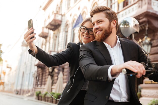 Sonriente pareja elegante sentado en moto moderna al aire libre