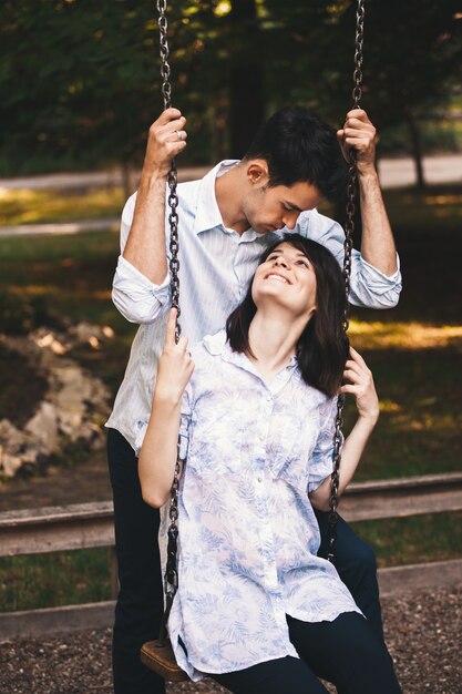 Sonriente pareja de enamorados en un columpio al aire libre.