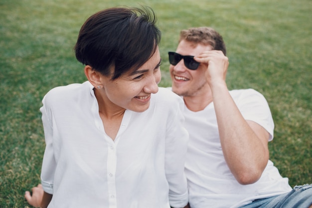 Foto gratuita sonriente pareja se encuentra en el césped verde