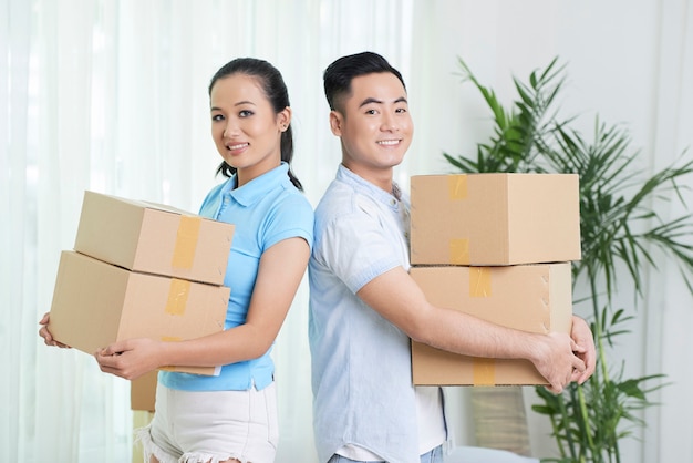 Sonriente pareja étnica con cajas de cartón