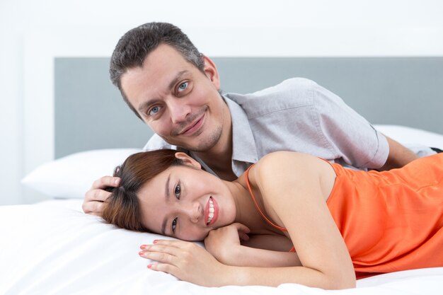Sonriente pareja joven acostado en la cama