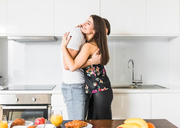 Sonriente, pareja joven, posición, en, cocina, se abrazar