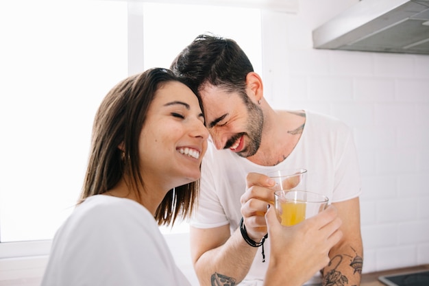 Sonriente pareja con jugo tocando las frentes