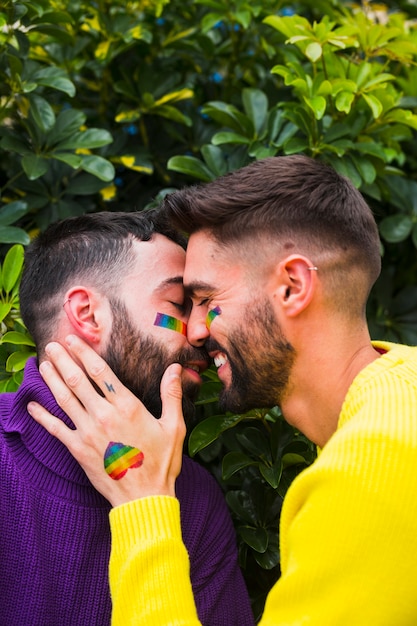 Sonriente pareja masculina besándose en el jardín