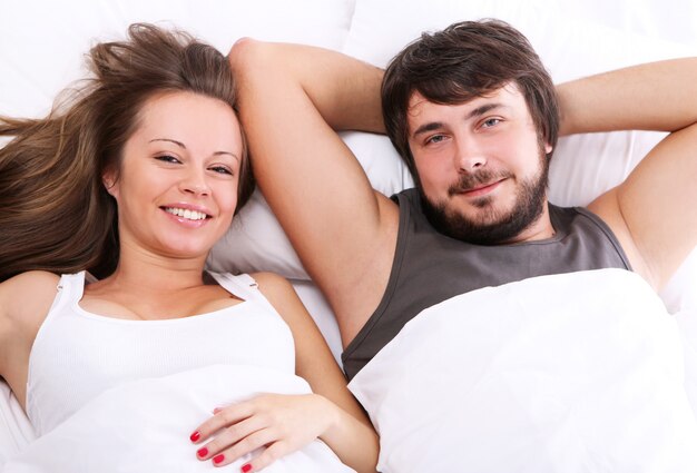 Sonriente pareja relajarse en la cama