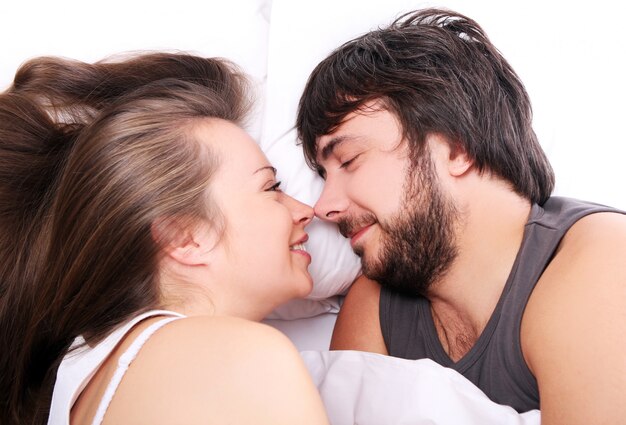 Sonriente pareja relajarse en la cama